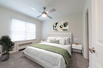 Modern bedroom at Monon Court Apartments Broad Ripple with ceiling fan, large window, and comfortable one- and two-bedroom floor plans near Monon Trail.